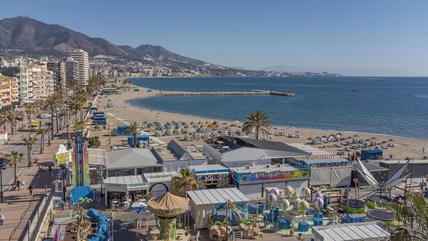 Paesaggio costiero con spiaggia, molo e diversi esercizi commerciali, tra cui un PlayZone.