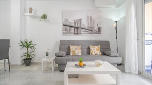 Un soggiorno moderno con un divano grigio, un tavolino da caffè bianco e un dipinto raffigurante un panorama urbano.