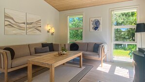 A living room with a wooden coffee table, two sofas, and a large window with a view of greenery. - Amazing home in Hals with kitchen (Hals)