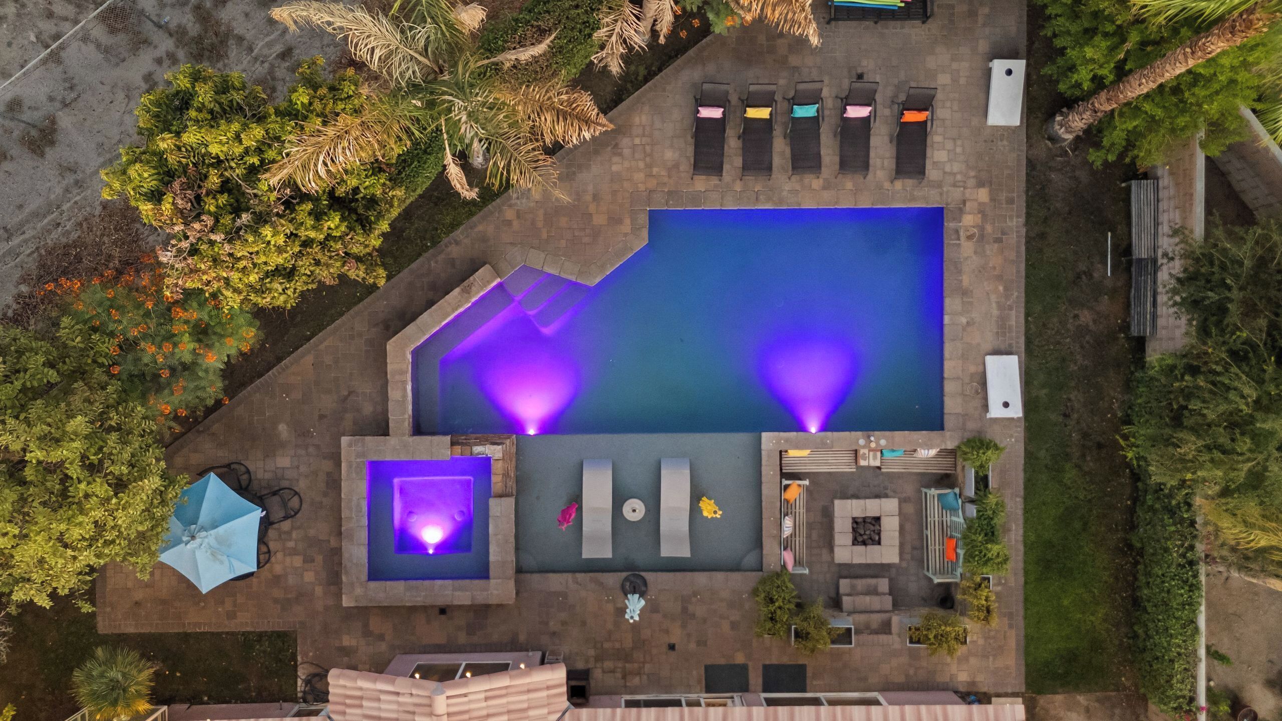 An aerial view of a swimming pool area with a hot tub, lounge chairs, and a small deck.