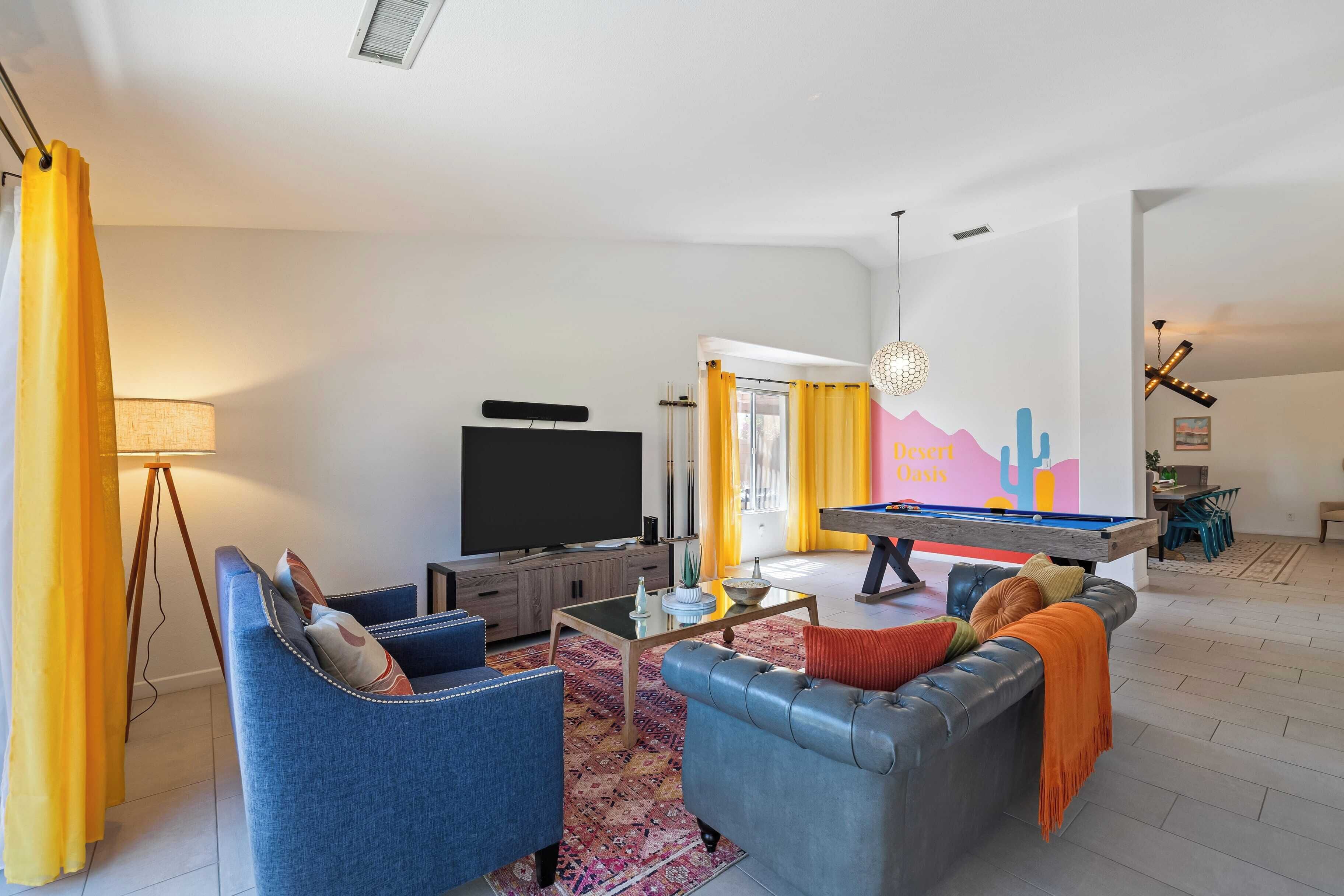 Una sala de estar con televisión, sofás, una mesa de centro y una mesa de billar.