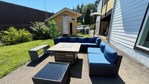 An outdoor seating area with a large sectional sofa, a rectangular table, and two square ottomans. - Convenient modern 2br home, 5 mins from airport. (Tukwila)