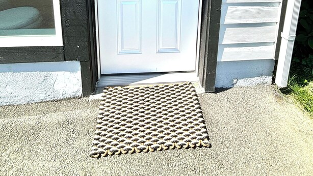 A white door with a wreath, a black door frame, and a small step with a textured mat. - Convenient modern 2br home, 5 mins from airport. (Tukwila)