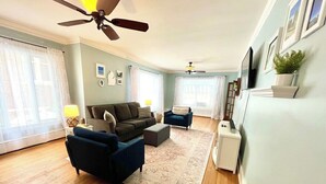 Un salon comprenant un canapé, deux fauteuils, une table basse, un tapis et un ventilateur de plafond.