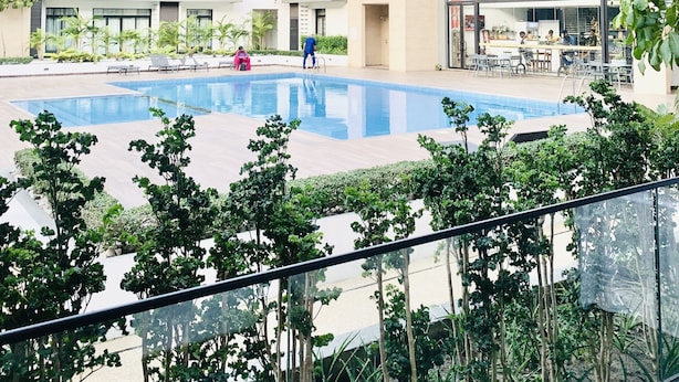 Ein modernes, mehrgeschossiges Gebäude mit einem zentralen Schwimmbad, Sitzgelegenheiten im Freien und einer Bar.