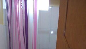 A bathroom with a toilet, a shower area, and a tiled floor.