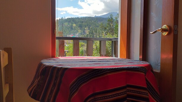 A room with a view of a mountainous landscape through a balcony door.