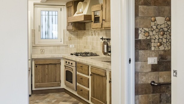 A kitchen with wooden cabinets, a gas stove, an oven, and a window. - S291 - Sirolo, new three-room townhouse in the historic centre (Sirolo)