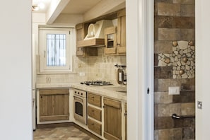 A kitchen with wooden cabinets, a gas stove, an oven, and a window.