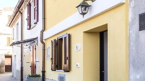 A yellow building with a stone base, a door, and a window with shutters. - S291 - Sirolo, new three-room townhouse in the historic centre (Sirolo)