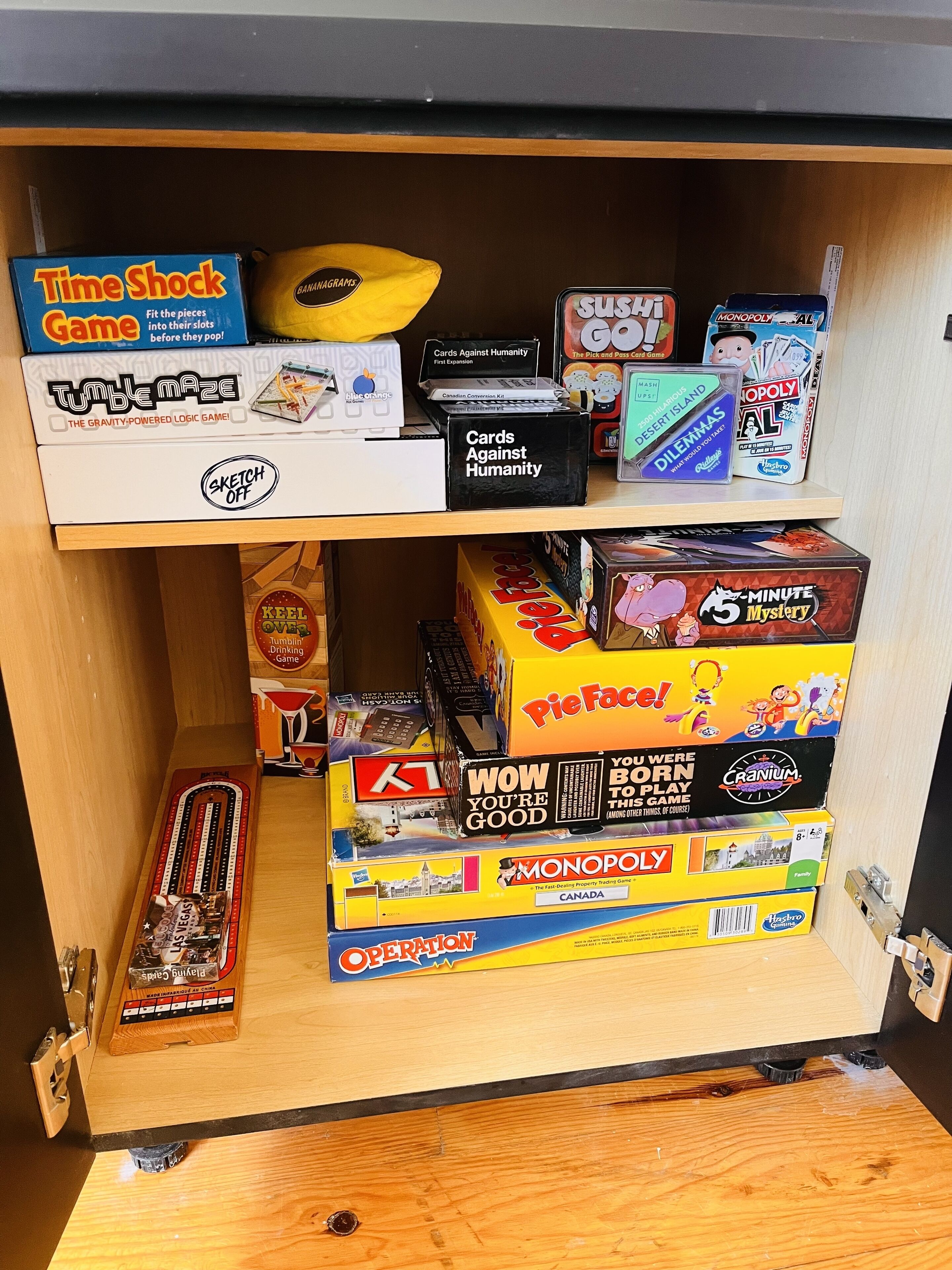 Una estantería con diversos juegos de mesa, incluyendo Time Shock Game, Table Maze y Monopoly.
