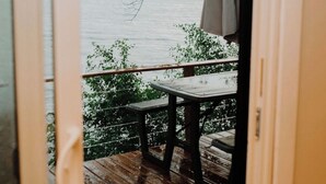 A wooden deck with a table and chairs, overlooking a body of water and trees. - Upper Rideau - “The West” Resort (Portland)