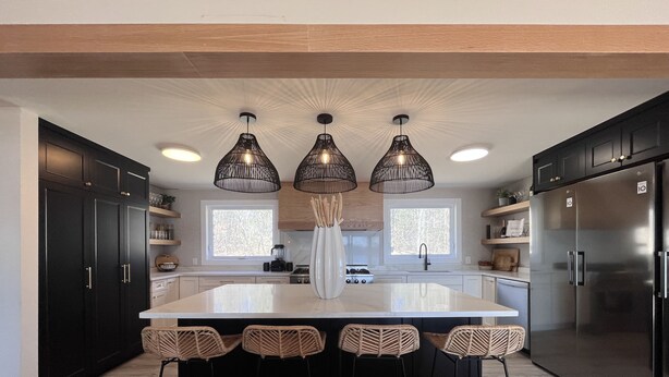 A modern kitchen with a central island, black cabinets, stainless steel appliances, and three hanging pendant lights. - Upper Rideau - “The West” Resort (Portland)