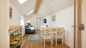 Un espai habitable pràctic amb zona de menjador, petita cuina i un racó agradable per seure amb sofà i televisió.