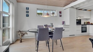 A modern kitchen with white cabinets, a dining area with a glass table, and a wooden ceiling. - 3 bedroom amazing home in Mariager (Mariager)