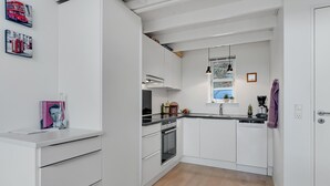 A modern kitchen with white cabinetry, a built-in oven, and a black countertop. - 3 bedroom amazing home in Mariager (Mariager)
