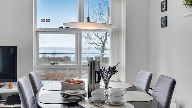 A modern dining area with a large window, a table set for two, and a kettle. - 3 bedroom amazing home in Mariager (Mariager)