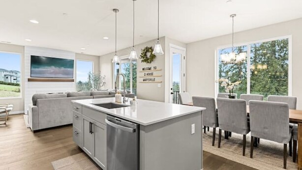 A modern kitchen with a central island, grey cabinetry, and pendant lighting.