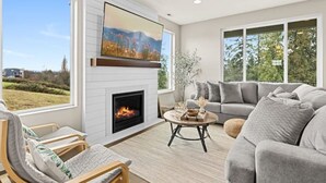 A living room with a fireplace, a sofa, a coffee table, and a TV mounted above the fireplace.
