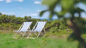 Due poltrone a righe in un'area verde con vista sul mare.