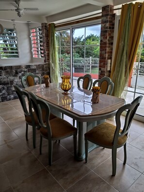 Un comedor con una mesa de vidrio, sillas y un florero.