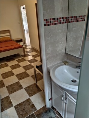 Un dormitorio con piso a cuadros, una cama con cubrecama naranja y una mesita de noche.