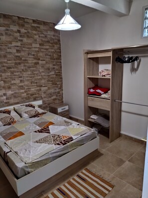 Un dormitorio con cama, mesita de noche, armario e iluminación colgante.