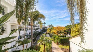 A pathway leading to a building with multiple floors, surrounded by lush greenery and palm trees. - Bahia Real apartment with large terrace (Marbella)