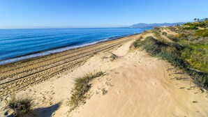 A coastal landscape with a sandy beach, a clear blue sky, and distant mountains. - Bahia Real apartment with large terrace (Marbella)