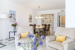 A modern living room with two sofas, a dining table, and a cabinet.