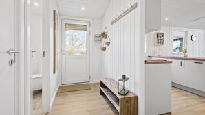 Une cuisine moderne avec des meubles blancs, un banc en bois et un luminaire suspendu.