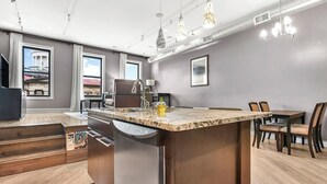 A modern kitchen with a large island, stainless steel appliances, and pendant lighting.