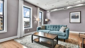 A modern living room with a teal sofa, a wooden coffee table, and a patterned rug.