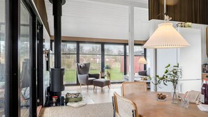 Una sala de estar moderna con un ventanal grande, una chimenea y un comedor con mesa y sillas.