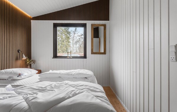 Une chambre avec deux lits, une fenêtre donnant sur des arbres, un miroir et une lampe.