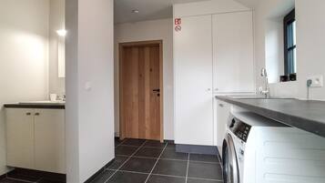 A modern kitchen with a built-in washing machine, a wooden door, and a tiled floor.
