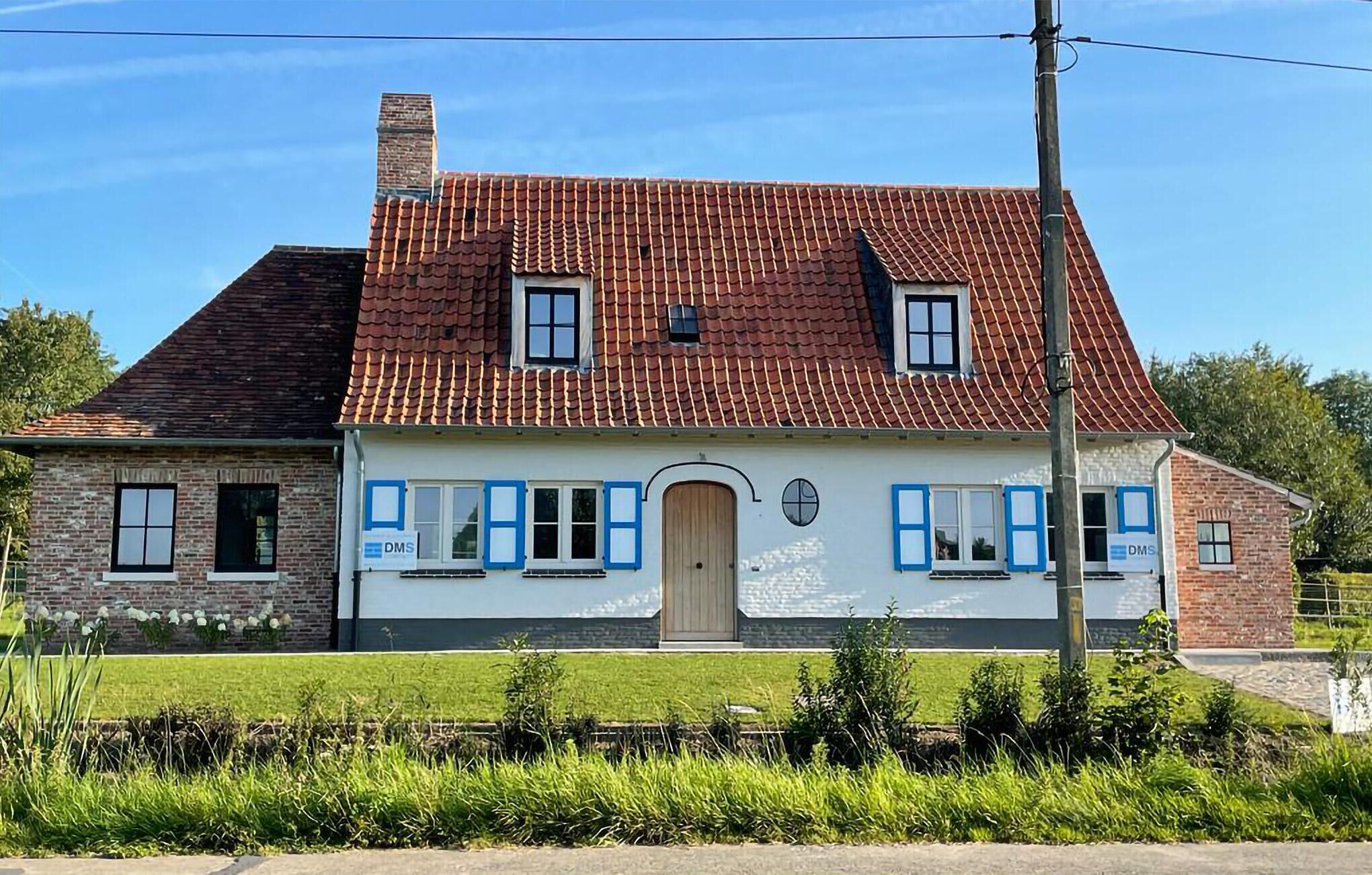 A two-story house with a red-tiled roof, a brick facade, and a small front garden.