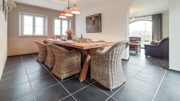 A dining area with a wooden table, wicker chairs, and a chandelier.