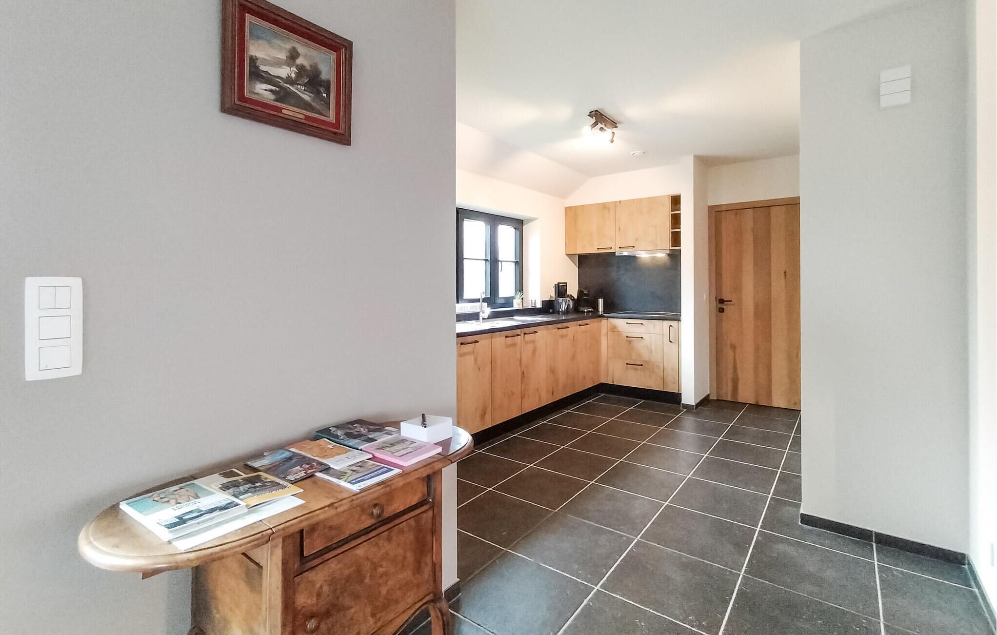 A modern kitchen with wooden cabinets, a black countertop, and a tiled floor.