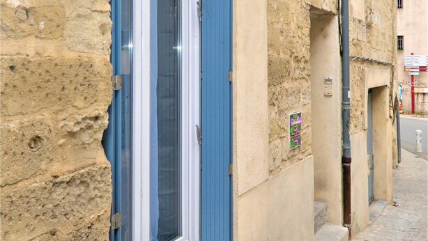 A building with a blue-framed window, a small window with a flower display, and a sign with directions. - Beautiful home in Sommières with WiFi (Sommières)