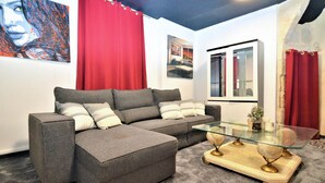 A modern living room with a grey sectional sofa, a glass coffee table, and red curtains. - Beautiful home in Sommières with WiFi (Sommières)