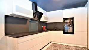 A modern kitchen with white cabinets, black countertops, a microwave, and an oven. - Beautiful home in Sommières with WiFi (Sommières)