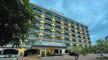 A multi-story hotel with a prominent 'Delta Hotels' sign, featuring balconies with lights, a brick-paved entrance, and a landscaped garden area.