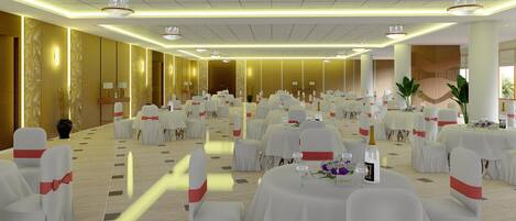 A banquet hall with round tables, white chairs with red sashes, and chandeliers.