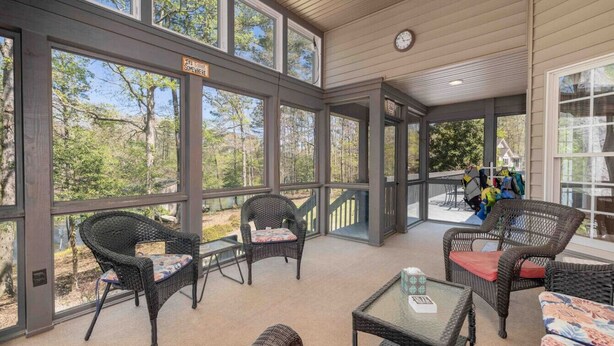 A covered outdoor patio with wicker furniture and large windows.