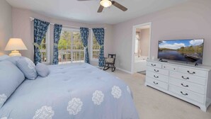 A bedroom with a large bed, a ceiling fan, a TV, and a dresser.