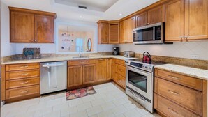 Een keuken met houten kasten, een rvs magnetron, een oven en een vaatwasser.