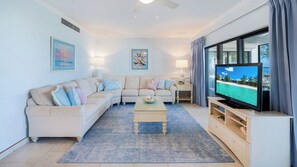 A living room with a sofa, coffee table, TV, and artwork on the walls.