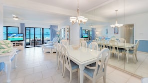 A spacious living room with a large TV, comfortable seating, and a view of the ocean.