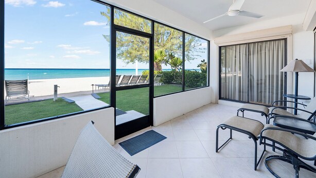 Ein Zimmer mit großen Fenstern, einem Deckenventilator und Blick auf den Strand.